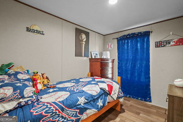 223 Primrose Lane Baxley, GA 31513 - Photo 16 of 27 a bed sitting in a bedroom next to a wooden door