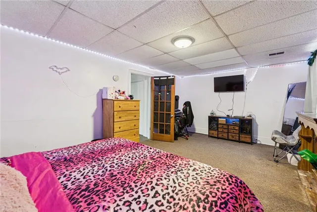 a bedroom with a bed a dresser and a large window