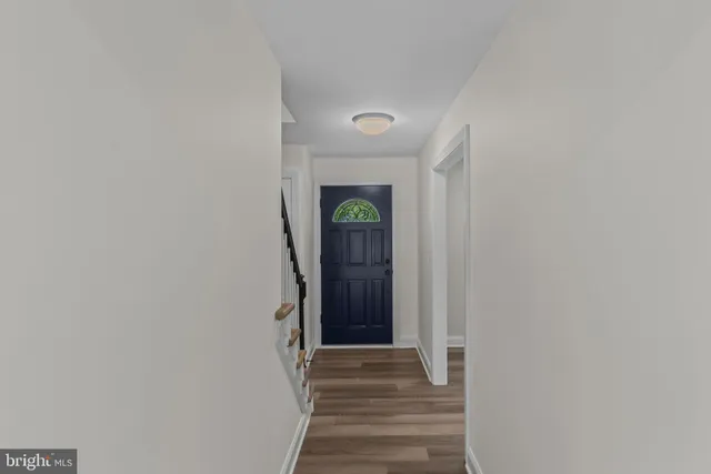 a large kitchen with stainless steel appliances a stove top oven a sink dishwasher a refrigerator white cabinets and wooden floor