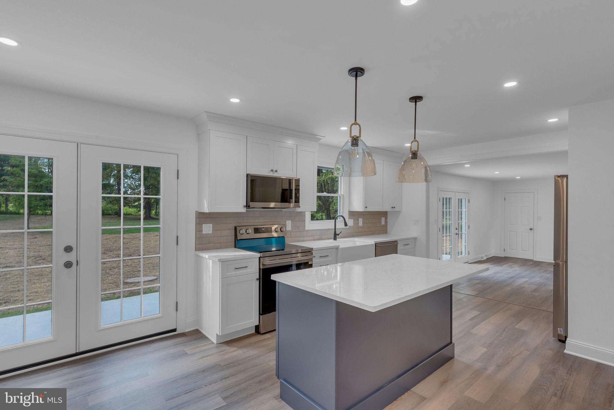 5925 Corrigan Road Doylestown, PA 18902 - Photo 9 of 64 a large kitchen with stainless steel appliances a stove top oven a sink dishwasher a refrigerator white cabinets and wooden floor