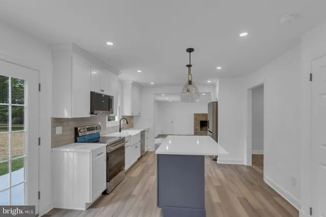 a kitchen with stainless steel appliances granite countertop a sink a stove and a wooden floors