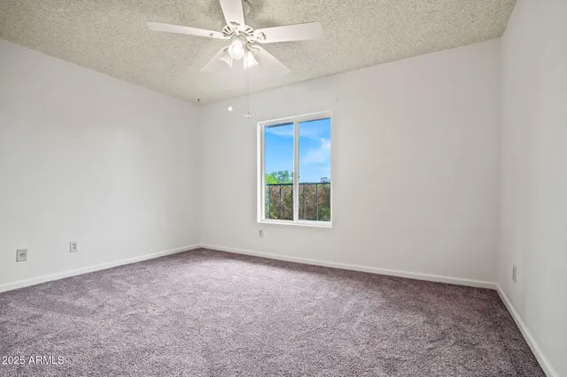 an empty room with a window and a fan