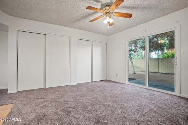 an empty room with windows and fan