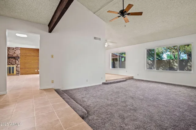 an empty room with windows and ceiling fan