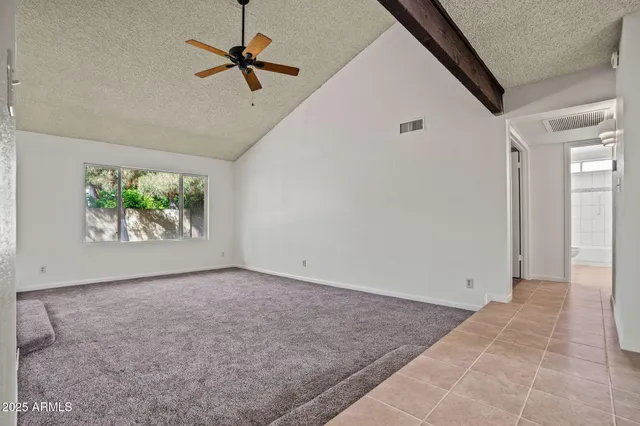 an empty room with windows and ceiling fan