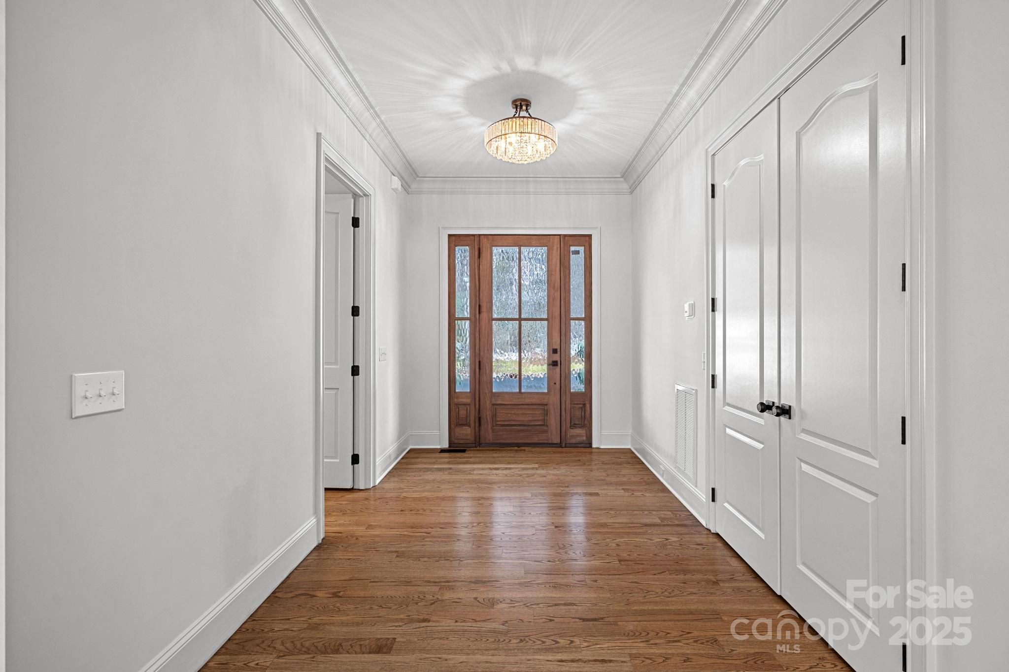 357 Magnolia Street Davidson, NC 28036 - Photo 3 of 48 a view of a hallway with wooden floor and a chandelier