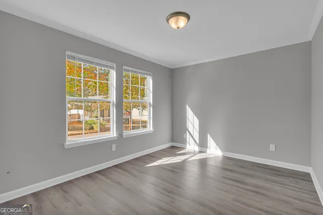 a view of empty room with wooden floor and fan
