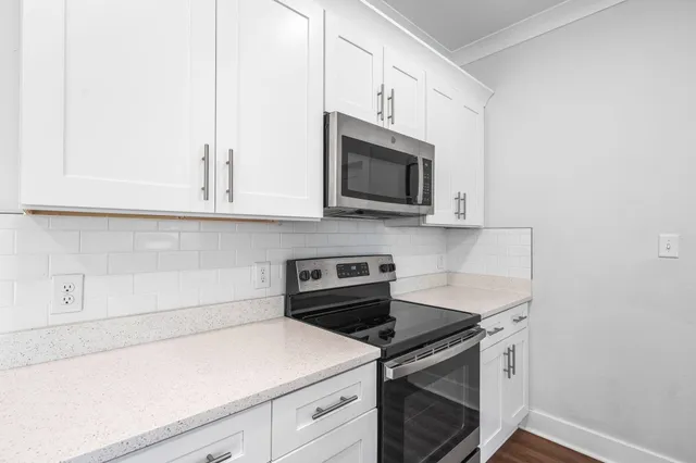 a large kitchen with stainless steel appliances granite countertop a stove and a wooden floors