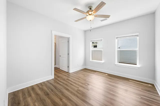 an empty room with wooden floor and windows