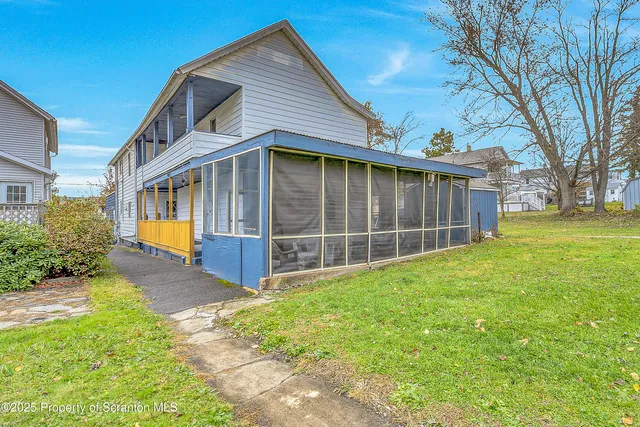a view of a house with a yard and a large tree