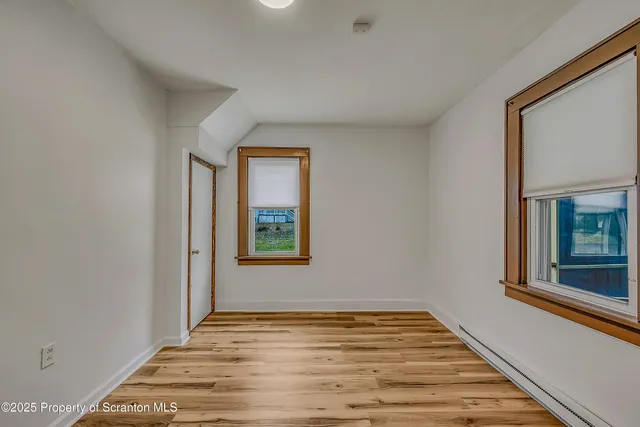 a view of a hallway with wooden floor and a bathroom