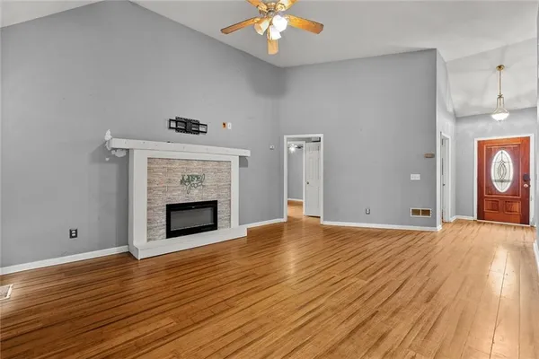 a view of an empty room with wooden floor fireplace and a window