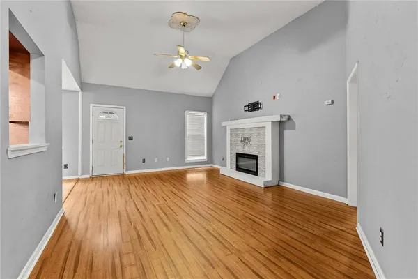 a view of an empty room with wooden floor and fireplace