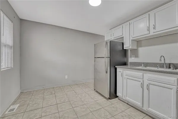 a kitchen with white cabinets and refrigerator