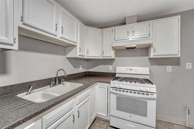 a kitchen with granite countertop white cabinets and white appliances