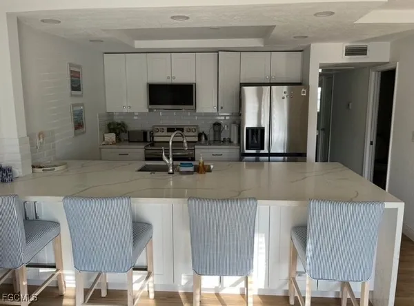 a kitchen with stainless steel appliances granite countertop a sink a microwave refrigerator and chairs