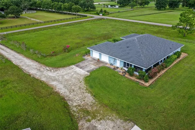a view of a house with a big yard and a large trees