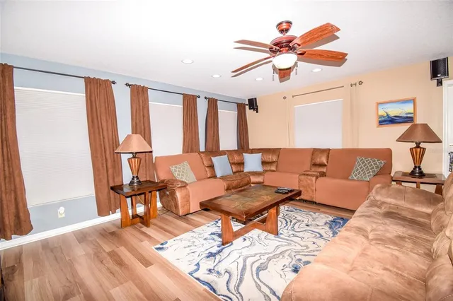 a living room with furniture a flat screen tv and a floor to ceiling window