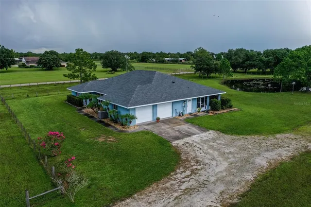 a view of a house with a big yard plants and large trees