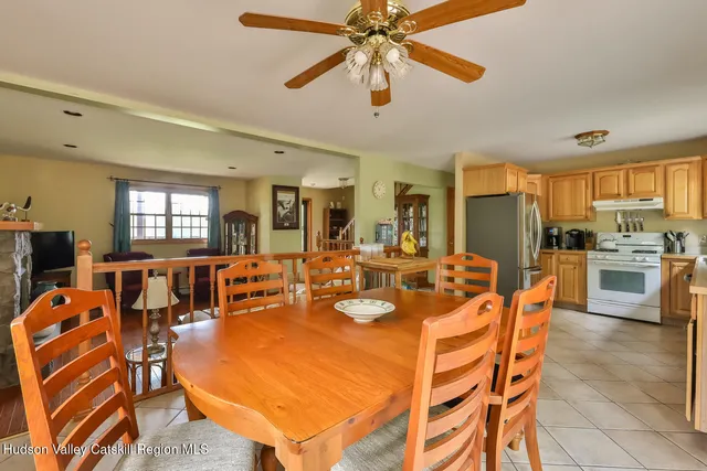 a dining room with furniture a chandelier a large window and stainless steel appliances