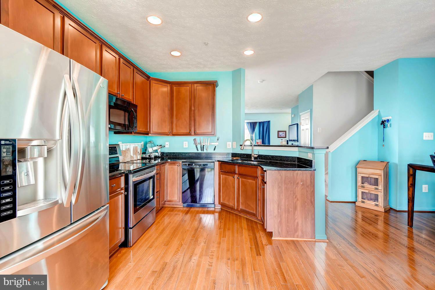 9714 Langley Road Baltimore, MD 21220 - Photo 9 of 27 a kitchen with stainless steel appliances granite countertop a refrigerator a stove top oven and wooden floors