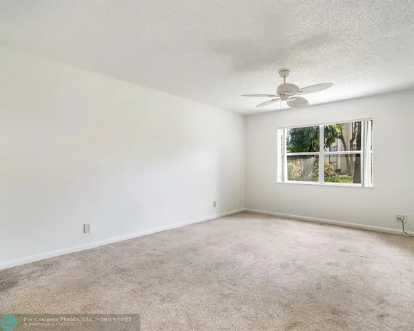 an empty room with windows and ceiling fan