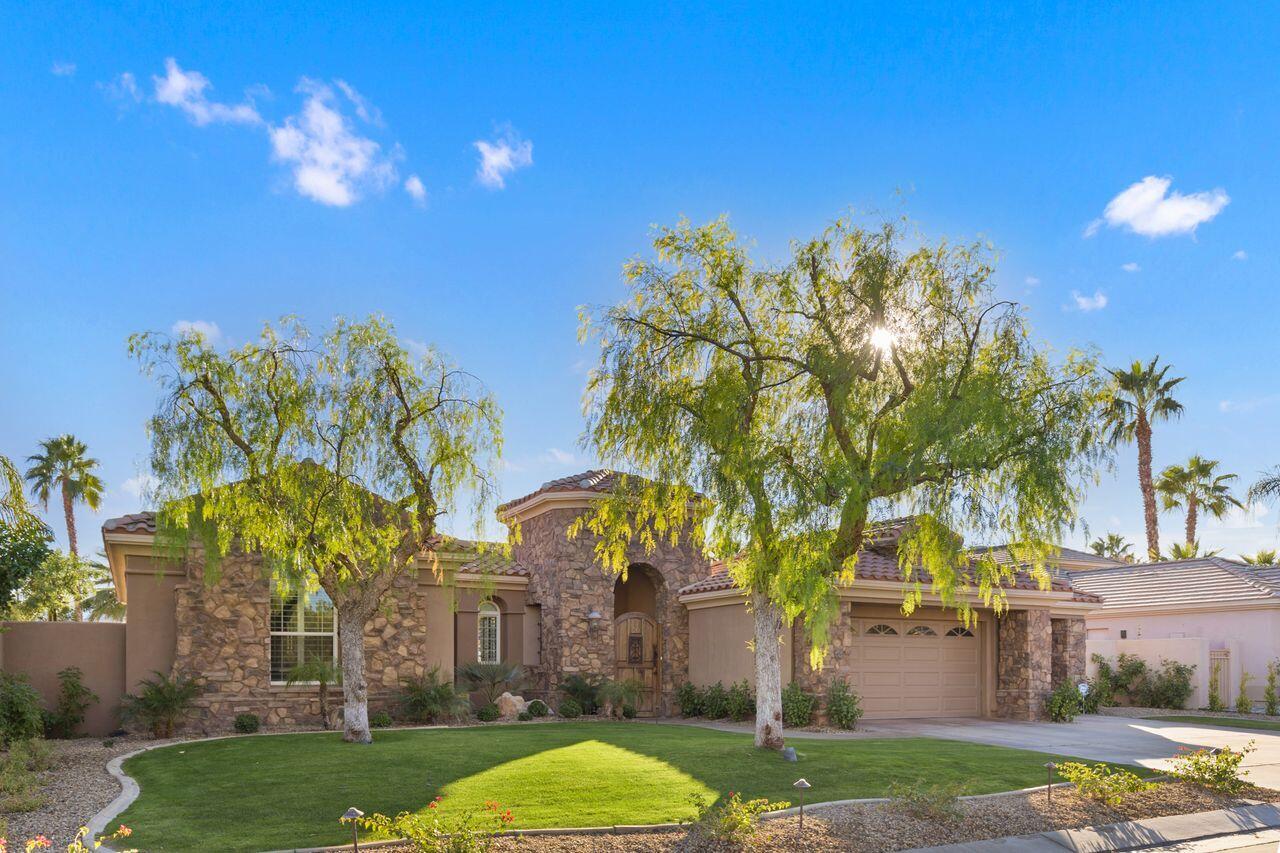 a view of a white house with a big yard and palm trees