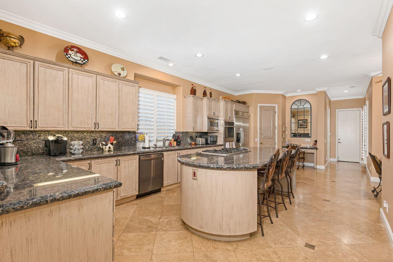 20 Vista Encantada Rancho Mirage, CA 92270 - Photo 11 of 37 a kitchen with stainless steel appliances granite countertop a stove top oven a sink a dining table and chairs