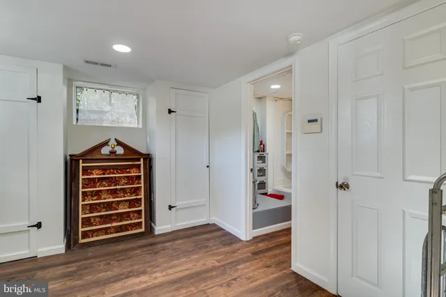 an empty room with wooden floor closet and windows