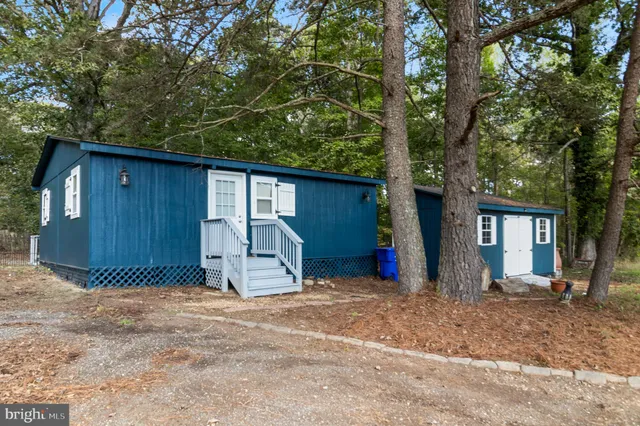 a view of a house with a large tree and wooden fence