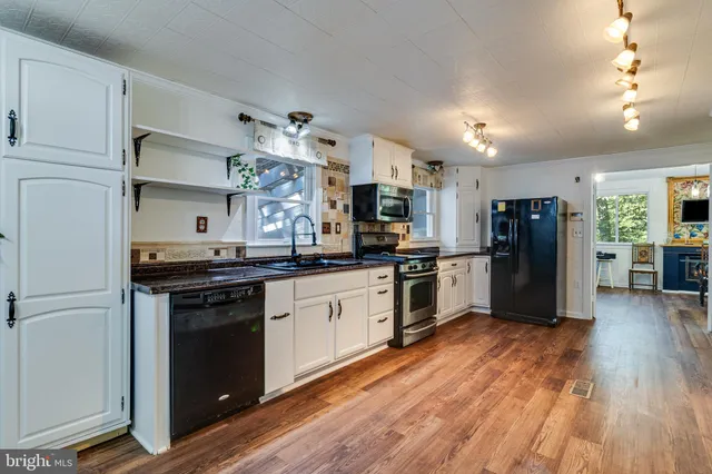 a kitchen with granite countertop a refrigerator stove top oven and cabinets