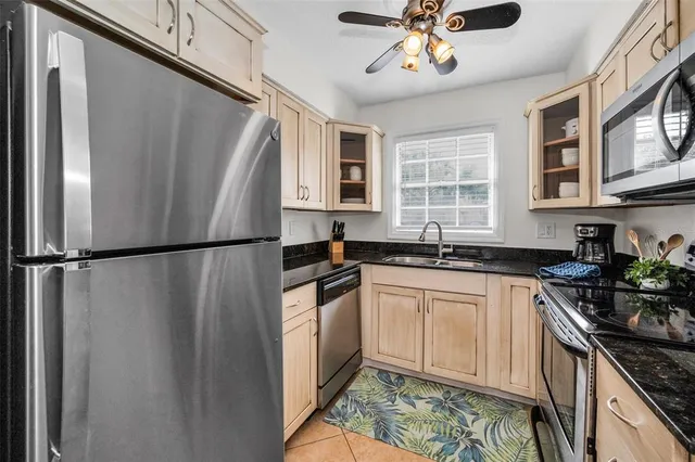 a kitchen with stainless steel appliances granite countertop a refrigerator a sink dishwasher a stove and white countertops with wooden floor