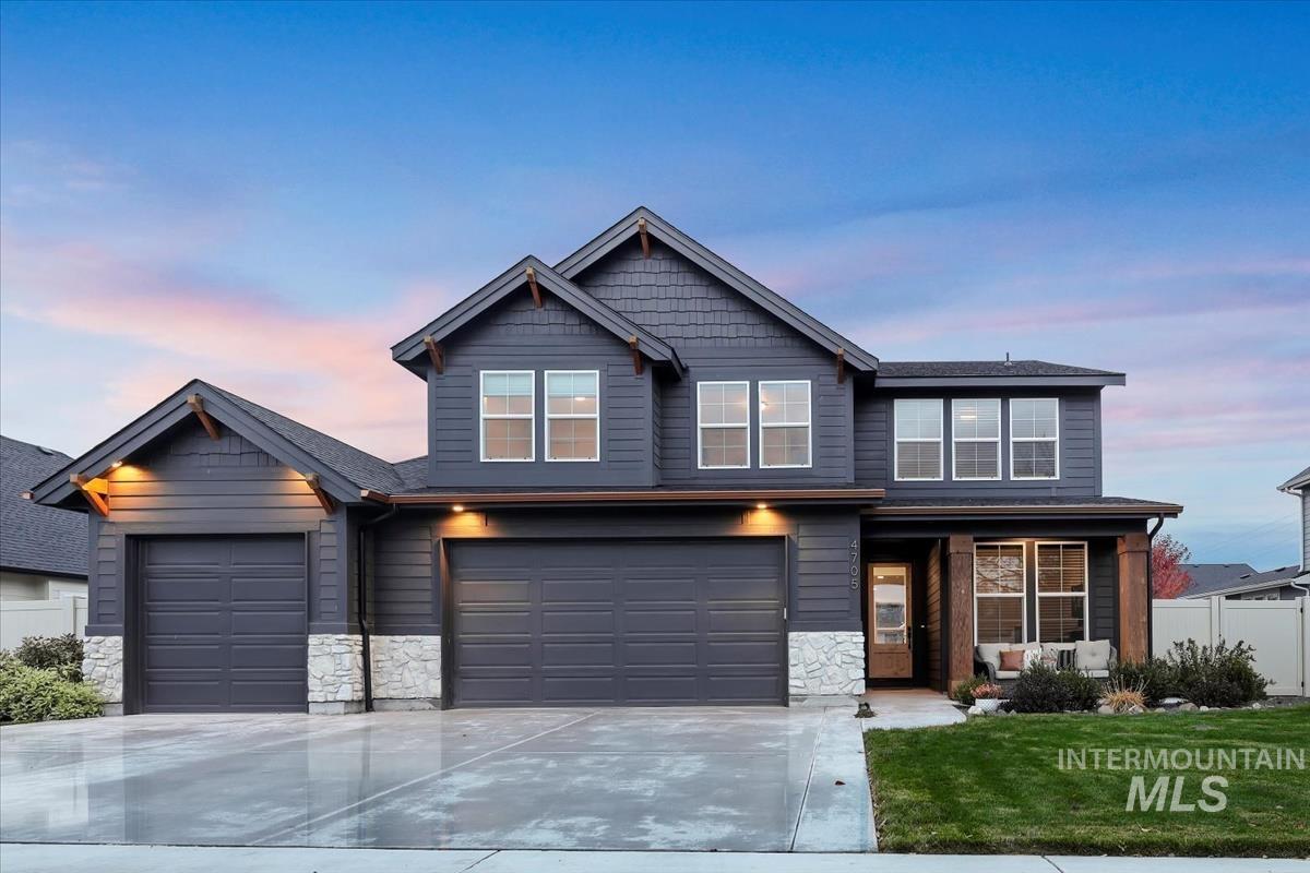 View of front of property featuring stone siding, driveway, and an attached garage