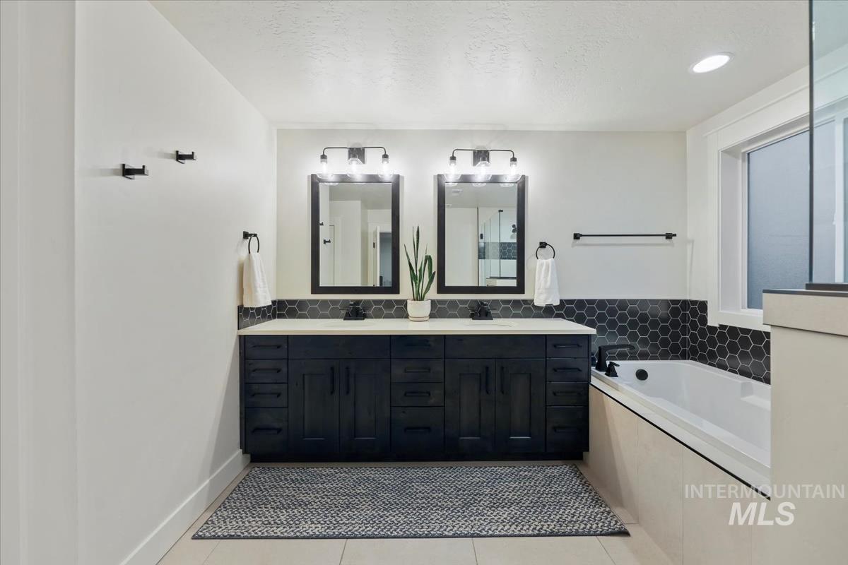 4705 North Morpheus Place Meridian, ID 83646 - Photo 26 of 45 Bathroom featuring light tile patterned floors, double vanity, a textured ceiling, and a bath