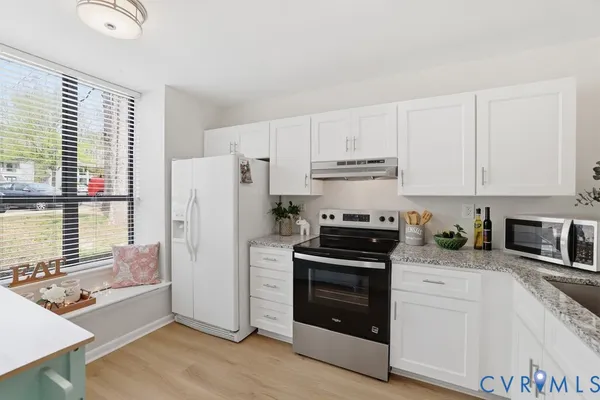 a kitchen with granite countertop white cabinets and appliances