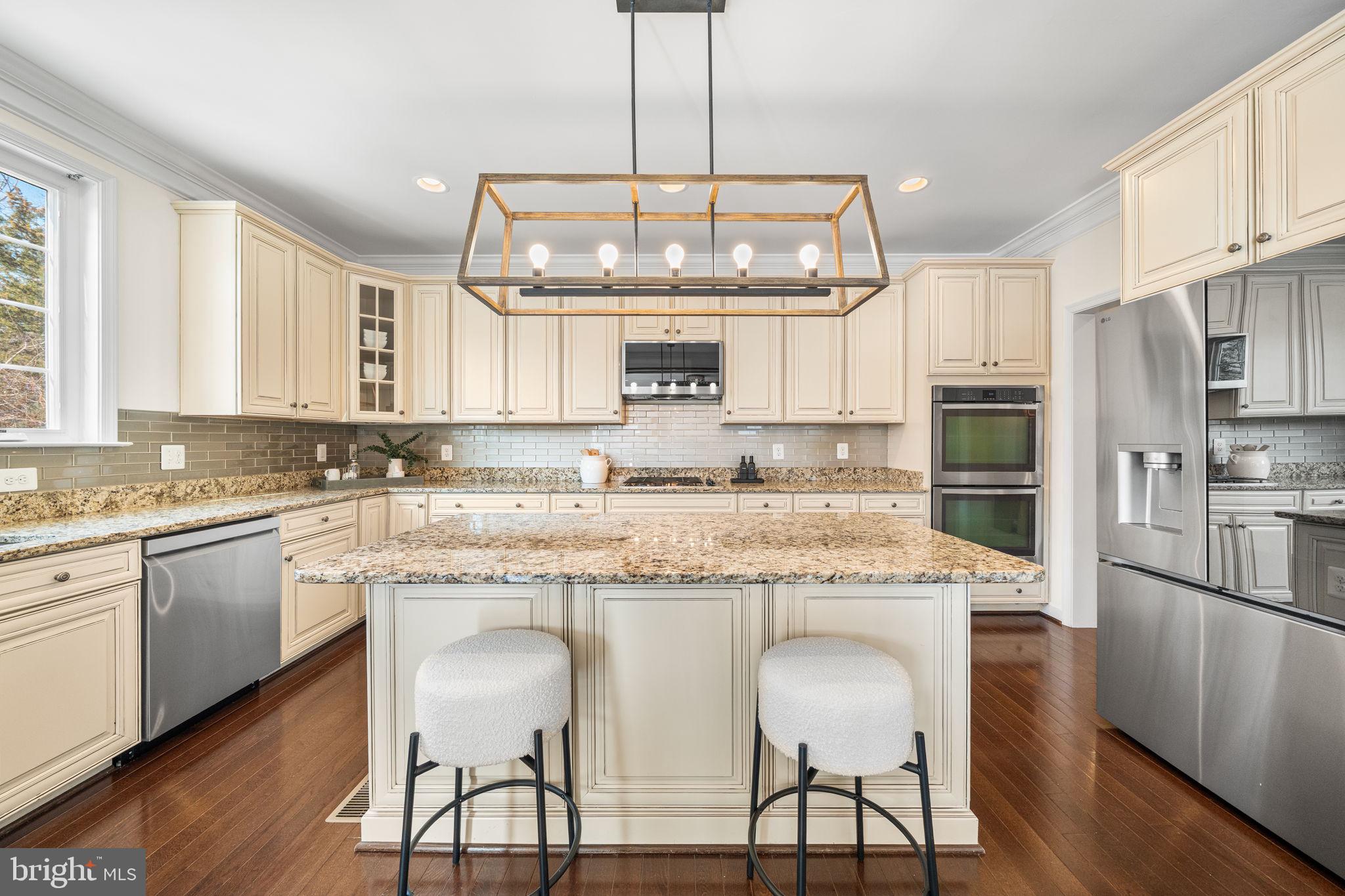 8032 Washington Road Alexandria, VA 22308 - Photo 19 of 50 a kitchen with stainless steel appliances granite countertop a stove top oven a refrigerator a sink and white cabinets with wooden floor