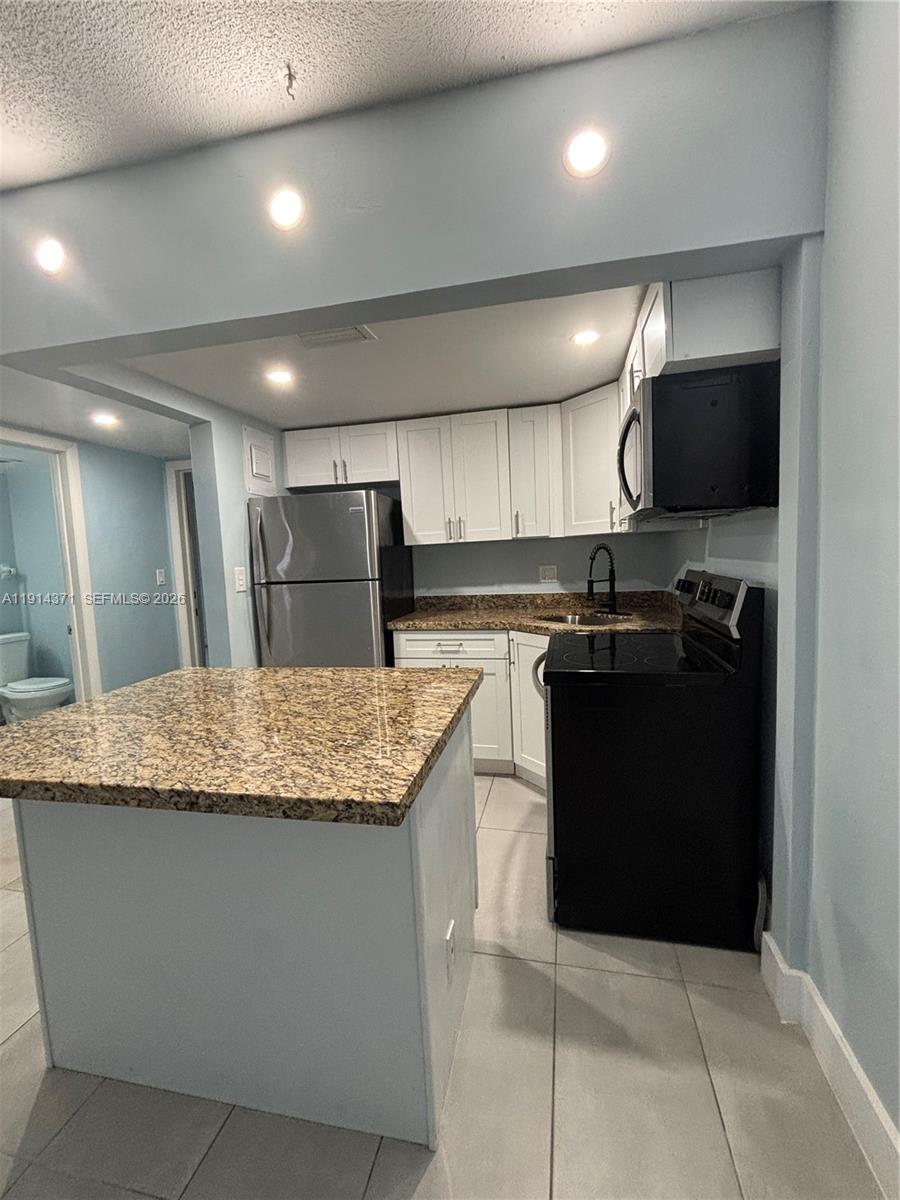 a kitchen with kitchen island granite countertop a sink counter top space cabinets and stainless steel appliances
