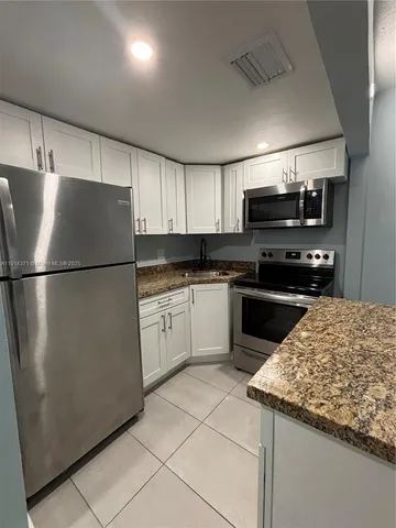 a kitchen with a sink a refrigerator and cabinets