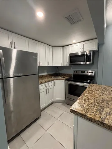 a kitchen with a sink a refrigerator and cabinets