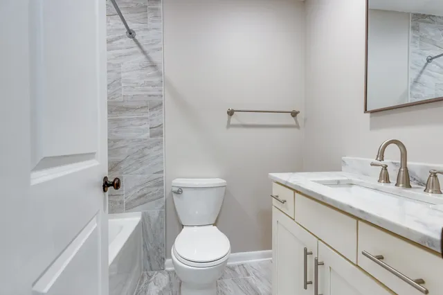 a bathroom with a granite countertop toilet and a sink
