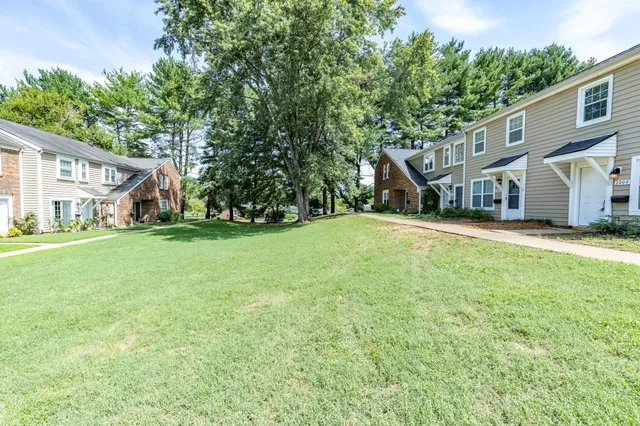 a view of a house with a big yard and large trees
