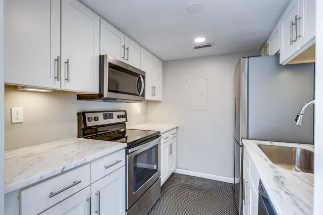 a kitchen with granite countertop a sink a stove and microwave