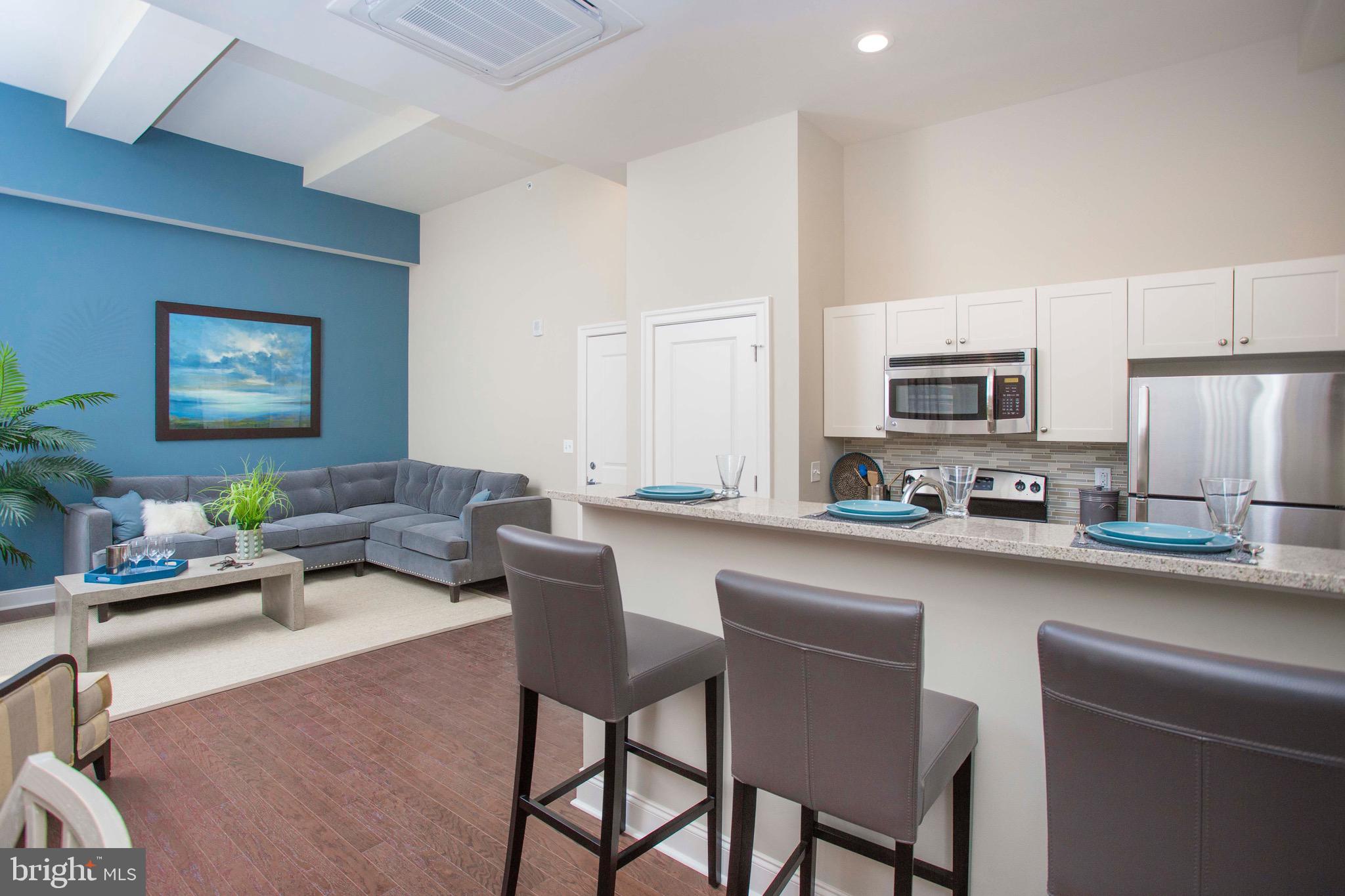 26 South Calvert Street, Unit 2BR Baltimore, MD 21202 - Photo 61 of 83 a living room with stainless steel appliances a dining table chairs and a refrigerator