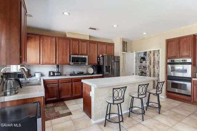 a kitchen with stainless steel appliances granite countertop a stove a sink a refrigerator and a refrigerator with wooden cabinets