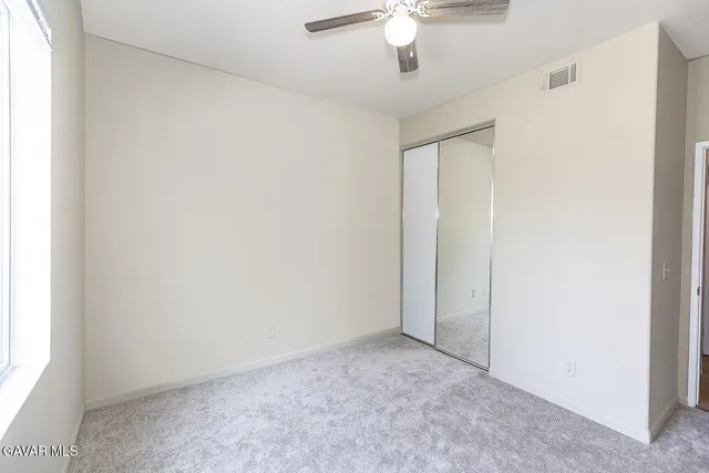 an empty room with a chandelier fan and a window