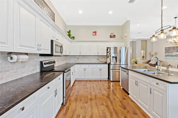 a large kitchen with stainless steel appliances granite countertop a stove a sink and white cabinets