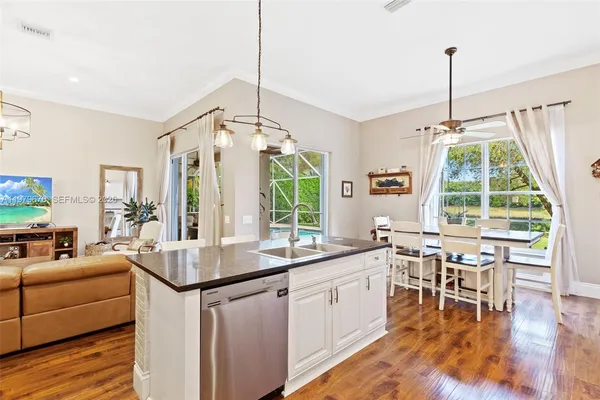 a view of a dining room and livingroom with furniture wooden floor a chandelier