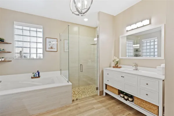 a bathroom with a tub sink double vanity and mirror