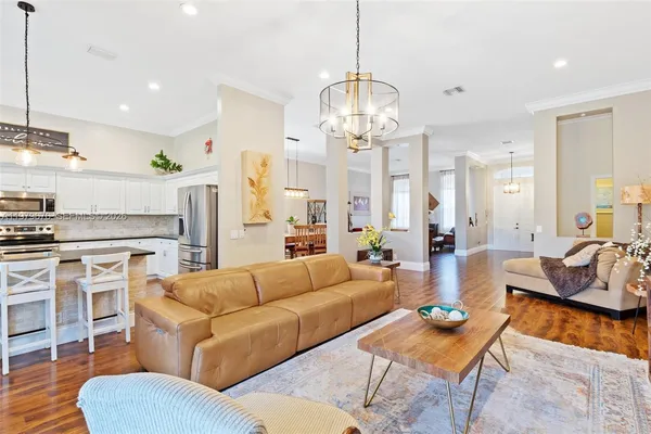 a living room with furniture kitchen view and a chandelier