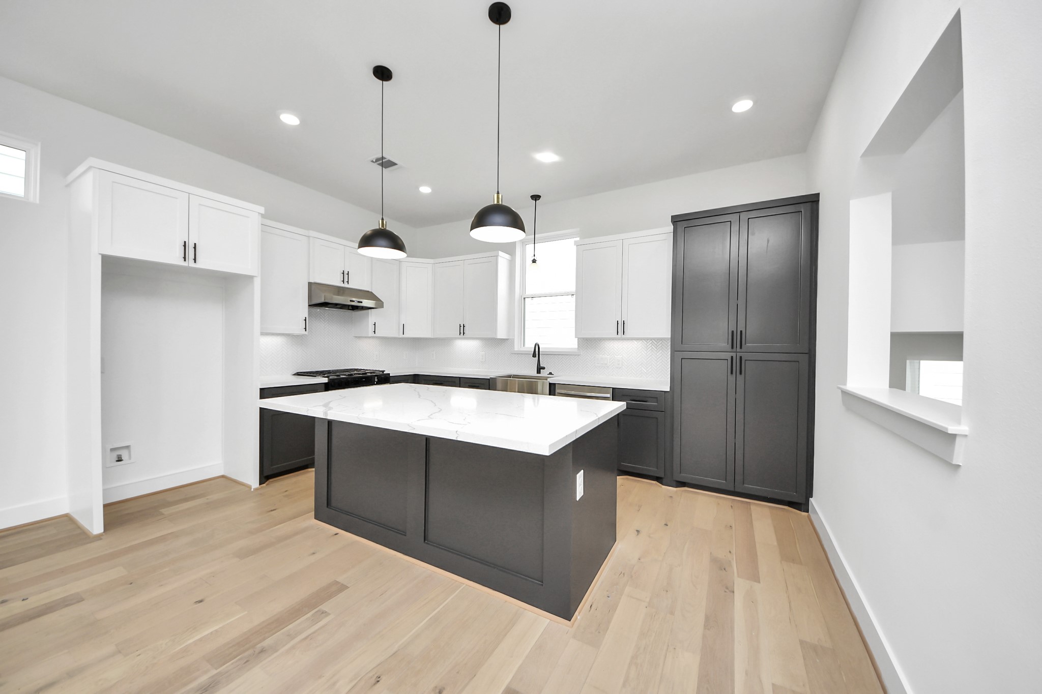 723 Marcella Street, Unit D Houston, TX 77091 - Photo 8 of 22 Chefs open kitchen and living space features stainless steel appliances, a modern island with a sink, quartz countertops, and custom black matte pendant lighting.